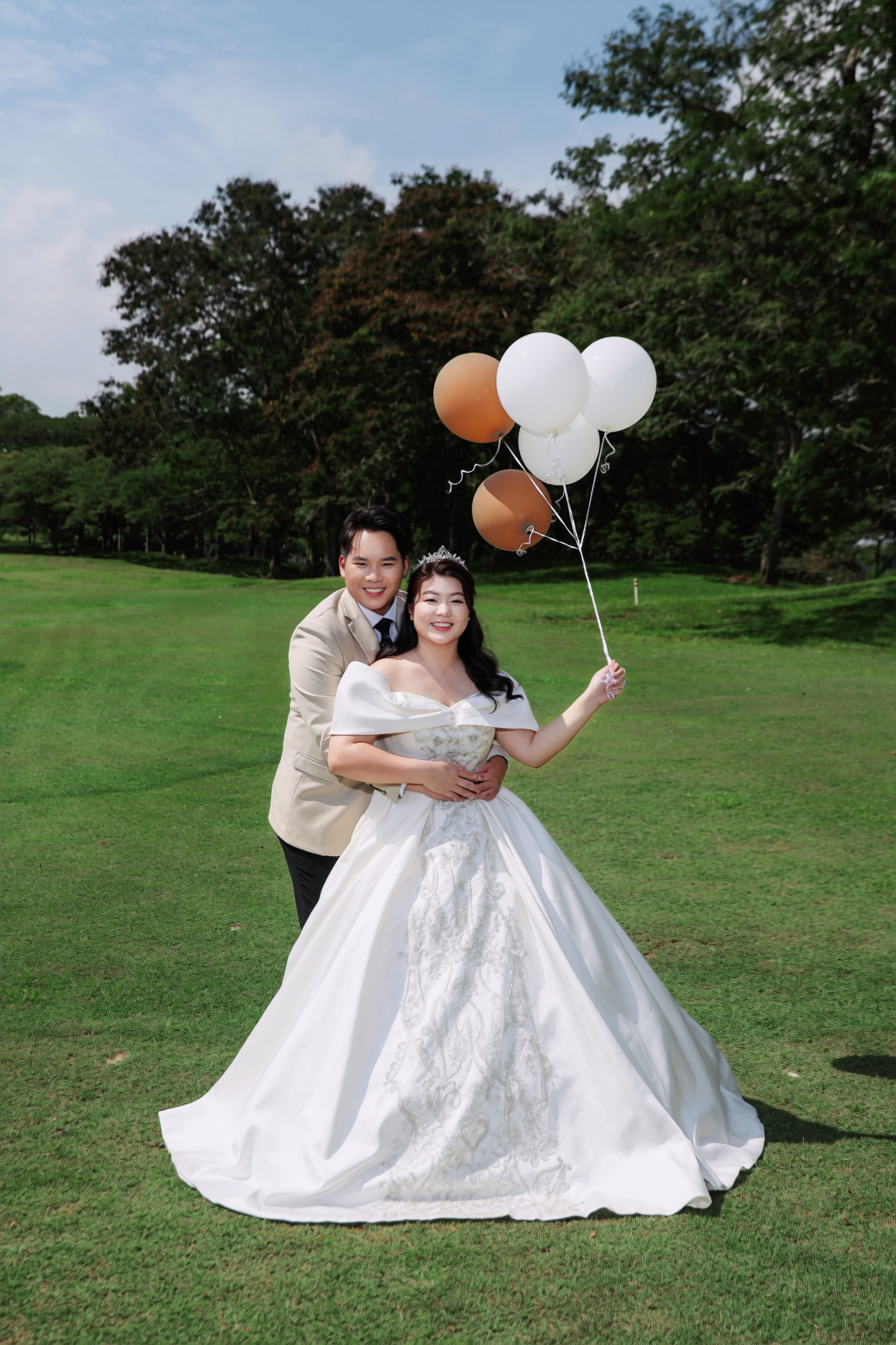 Anson and Jessy in wedding attire with balloons on a sunny lawn